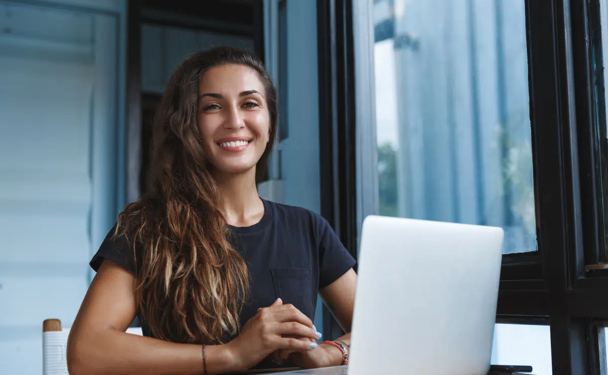 Donna sorridente in ufficio che esprime fiducia in se stessa, simbolo di crescita personale e autostima potenziata grazie al coaching professionale