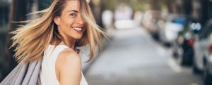 Donna sorridente che cammina all’aperto, simbolo di benessere, equilibrio interiore e felicità raggiunta grazie al coaching e alla crescita personale