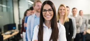 Donna leader che guida con sicurezza un gruppo di colleghi, simbolo della leadership empatica e del potenziamento personale attraverso il coaching professionale