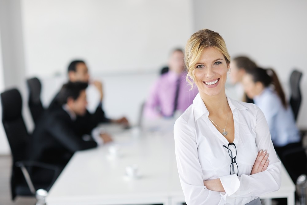 Donna bionda sorridente in ufficio, simbolo di leadership positiva, crescita aziendale e sviluppo professionale grazie al coaching strategico