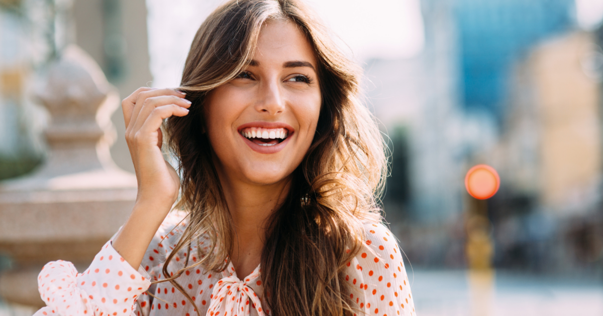 Donna sorridente e serena, simbolo di realizzazione personale, felicità e crescita interiore raggiunte grazie al coaching