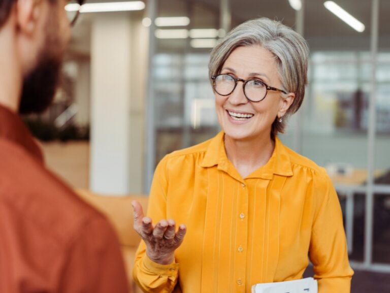Coach professionista che dialoga con un cliente in ufficio, simbolo di ascolto empatico, domande potenti e miglioramento continuo nelle tecniche di coaching