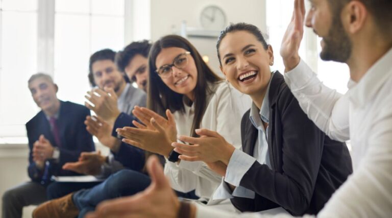 Team in ufficio che collabora con entusiasmo, simbolo di coaching aziendale, performance straordinarie, leadership consapevole e benessere organizzativo nelle imprese moderne